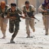 Kurdish fighters from the People's Protection Units (YPG) run across a street in Raqqa, Syria, July 3, 2017. 