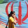 An Iranian man walks past an anti-US and anti-Israel mural painted on a wall, in the capital Tehran on May 10, 2026. 