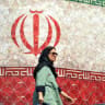 Una mujer pasa junto a una valla publicitaria en la que se ve la bandera nacional de Irán en la plaza Enghelab de Teherán, el 14 de junio de 2026. El presidente de EE. UU., Donald Trump, afirmó que el 14 de junio podría firmarse un acuerdo con Irán para poner fin a la guerra en Oriente Medio