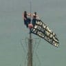 Two people display a banner atop the Empire State Building in the Manhattan borough of New York, US, July 1, 2026, in a still image from video.