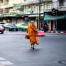 A Buddhist monk walks across a road while collecting alms in Bangkok early on April 28, 2026. 