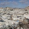Tents and makeshift shelters housing displaced Palestinians stretch amid the ruins of buildings near the al-Shati refugee camp, west of Gaza City, on July 1, 2026.