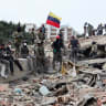 Rescuers search for victims at a collapsed building as one raises a Venezuelan flag following a magnitude 7.2 earthquake that struck Venezuela and other regions in the Caribbean, on June 28, 2026 in Caraballeda, La Guaira, Venezuela.