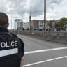 A police officer looks toward the scene of an antisemitic shooting attack (near the tall building at L) in Montreal on June 22, 2026, which left three people dead; Illustrative.