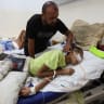 Injured Palestinian Hassan Qlob, 18, who his father says was shot in the head more than two months ago while out seeking food, lies on a bed as he waits for the Rafah crossing to reopen so he can receive treatment abroad, as his father Ibrahim tends to him, after the Israel-Hamas ceasefire.