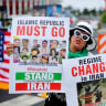A woman holds banners denouncing the Iranian regime, June 21, 2026; illustrative.