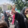 A mourner flashes a victory sign while under cool water sprayed by municipal workers after paying final respects to Iran's slain Supreme Leader Ayatollah Ali Khamenei during the third day of his funeral ceremonies on July 6, 2026 in Tehran, Iran.