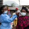 A health worker takes the temperature of a woman passing through the Kanyaruchinya checkpoint, as authorities and aid agencies intensify efforts to contain a new Ebola outbreak involving the Bundibugyo strain, in the northern entry into the city of Goma, North Kivu province, the Democratic Republic 