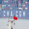 A Chinese national flag is seen in front of a CMA CGM container ship docked at Yantian Port on May 7, 2026.