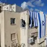 Israeli flags are displayed on a building that was damaged during the war against Iran