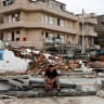 A person sits beside a collapsed wall in the aftermath of Typhoon Bavi in the coastal village of Dongsha, Taizhou, Zhejiang province, China, July 12, 2026.