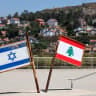 Representations of the Israeli and Lebanese flags at a memorial near the Israel-Lebanon border, as the town of Metula appears in the distance, June 27, 2026