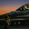 A US Air Force fighter pilot performs pre-flight checks on an F-16 fighter jet.
