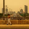 A woman walks on an overpass as wildfire smoke from northwestern Ontario, combined with an intense heat wave, fills the sky, prompting health warnings and calls for residents to limit outdoor activity in Toronto, Ontario, Canada, July 15, 2026.