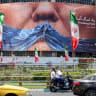 Motorists drive their vehicles past a political billboard featuring US President Donald Trump and the Strait of Hormuz along Valiasr Square in Tehran on May 26.