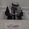 An elderly Palestinian man fills out his ballot before casting his vote at a polling station during municipal elections in the West Bank city of Hebron on April 25, 2026.