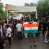 A supporter of India's Cockroach Janta Party (CJP) poses while holding the Indian national flag at a protest site, a day after thousands of protesters marched toward parliament demanding the resignation of the Education Minister over examination paper leaks, at Jantar Mantar in India, July 21, 2026.