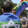 A participant draped in a rainbow flag with a Star of David marches with others towards Berlin's victory column during the 2025 Christopher Street Day CSD Berlin Pride march, in Berlin, Germany. July 26, 2025 