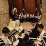 Young people in the foreground pray at the Western Wall during Tisha B'Av.