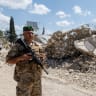 A Lebanese army officer stands beside a building damaged in an Israeli air strike, in Zawtar al-Gharbiyeh, a village in southern Lebanon, following the deployment of Lebanese soldiers in one of three pilot zones after the withdrawal of Israeli forces under a US-brokered plan, July 26, 20