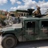 A Lebanese army officer looks up at an Israeli drone while standing on an armoured vehicle in Zawtar al-Gharbiyeh, a village in southern Lebanon, as Lebanese soldiers deploy in one of three pilot zones following the withdrawal of Israeli forces under a US-brokered plan, July 26, 2026. 