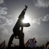 A Houthi follower rises a weapon as he attends a rally marking one year of Saudi-led air strikes, in Yemen's capital Sanaa.