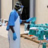 A Ugandan worker collects a rubber glove from the airing line during a visit by the Director-General of the World Health Organisation (WHO) Tedros Adhanom Ghebreyesus at the Mulago National Referral Hospital Isolation Unit, as aid agencies intensify efforts to contain a new Ebola outbreak.