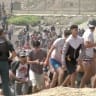 Migrants walk next to a USECIC Guardia Civil member after swimming through Spain's Ceuta border from the Moroccan side to reach the border fence, in Ceuta, Spain, July 30, 2026, in this screen grab obtained from a video