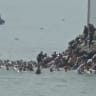 Migrants swim through Spain's Ceuta border from the Moroccan side and climb onto rocks to reach the border fence, in Ceuta, Spain, July 30, 2026, in this screen grab obtained from a video.