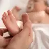 headline: Mother massages her baby’s feet with oil
