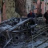 Residents look at a burned car at a site of a Russian missile strike, amid Russia's attack on Ukraine, in Kyiv region, Ukraine August 1, 2026. 