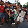 Migrants carry a fellow migrant, who they say was injured when the Spanish police and military tried to contain the migrants to an area of a beach, following mass crossings of migrants on foot and by sea from Morocco into Spanish territory, in Ceuta, Spain, August 2, 2026.