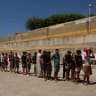 Migrants, some of them minors, queue to receive food staples from local NGO Media Luna Blanca in an industrial area where they are sleeping amid recent mass crossings by migrants on foot and by sea from Morocco into the Spanish territory, Migrants, some of them minorsin Ceuta, Spain, August 6, 2026.