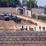  Israeli soldiers (top) stand guard next to settlers in front of the Palestinian houses in the village of Kusra, south of Nablus, in the occupied West Bank, on August 12, 2026.