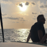 A man sits aboard one of the boats belonging to the Derech Hayam (Via Maris) yachting club and school. August, 2026.