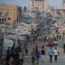 Displaced Palestinians walk past tents and destroyed buildings near the beachfront in Gaza City in August. 
