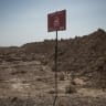 A sign warning of land mines stands in a mine field that stretches at least six kilometres along the route of an oil pipeline, south west of Raqqa city, Syria, June 3, 2025