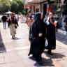 Women walk past shops at Valiasr Square in central Tehran on August 8, 2026.