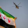 A military helicopter flies above a Syrian flag during the Syria Summer Family Festival in Damascus, Syria, on August 9, 2026. 