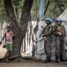 Indian peacekeepers serving with the United Nations Mission in South Sudan (UNMISS) stand guard next to a young boy as they patrol outside local government offices in the strategic opposition-controlled town of Akobo, Jonglei State, on February 12, 2026.