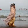 FILE PHOTO: People walk on the beach, with vessels in the Strait of Hormuz visible near the beach of Bandar Abbas, Iran, May 22, 2026.