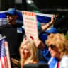 A demonstrator holds an Israeli flag as protesters gather during an '#EndJewHatred' rally outside Poetica Coffee, following a social media post by the shop targeting Jewish Congressman Dan Goldman and denying service to pro‑Israel customers in Brooklyn, New York.