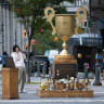 A man takes pictures of an "Iran war participation trophy" installation, placed by the protest group The Secret Handshake, in New York City, US, July 29, 2026. 