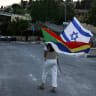 A woman carries a Druze and an Israeli flag as members of the Druze community in Israel and their supporters near the US Embassy in Jerusalem to show solidarity with their community in neighbouring Syria, on July 16, 2025.