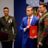 Secretary of War Pete Hegseth (C) poses for a photograph with Marine GySgt. Jonathan Eby (R) during an event to honor Marines who were serving during the 2021 Abbey Gate bombing, at the Pentagon on August 26, 2026 in Arlington, Virginia.