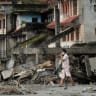 A woman walks past destroyed buildings after flash floods and mudslides, in Devighat, Nuwakot district, Nepal, August 29, 2026.