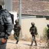 Israeli leftist activists gather as Palestinian residents and solidarity volunteers stand on the roof of a house besieged by Israeli settlers in the village of Qusra, south of Nablus, West Bank, August 14, 2026