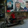 A man drives a tuk-tuk past portraits of late Palestinian President Yasser Arafat (C) and former Fatah security chief in Gaza Mohammed Dahlan (R) in Beirut's Burj al-Barajneh camp for Palestinian refugees on May 14, 2024; illustrative.