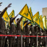 Hezbollah members salute and raise the group's yellow flags during a funeral.