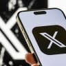 In this photo illustration, a smartphone shows the updated app icon for X, with a black background, while the previous version of the X logo is seen in the background, on August 20, 2025 in Chongqing, China; illustrative